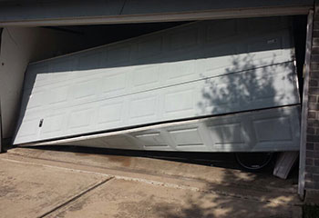 Technician repairing off-track garage door and bent tracks