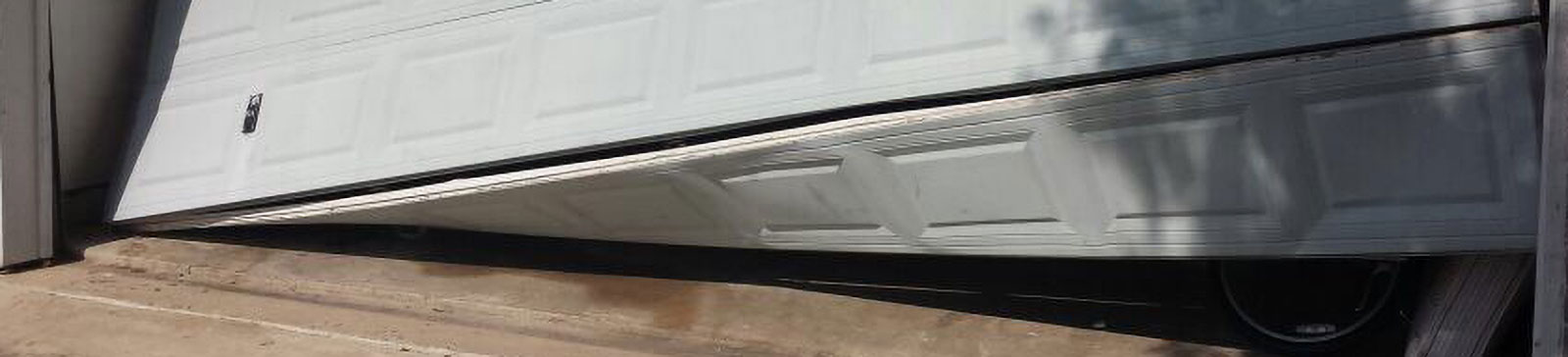 Technician repairing off-track garage door and bent tracks